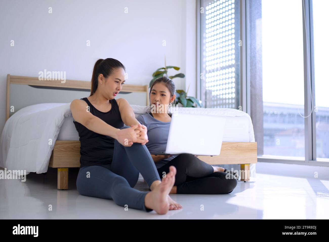 Two women paly yoga at home. Healthy lifestyle and leisure concept. Stock Photo
