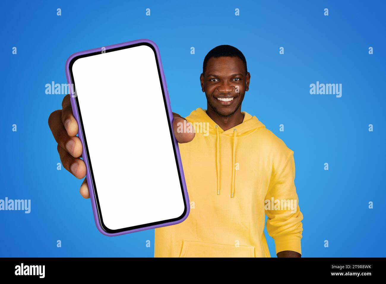 Smiling black man holds cellphone empty screen on blue background Stock Photo