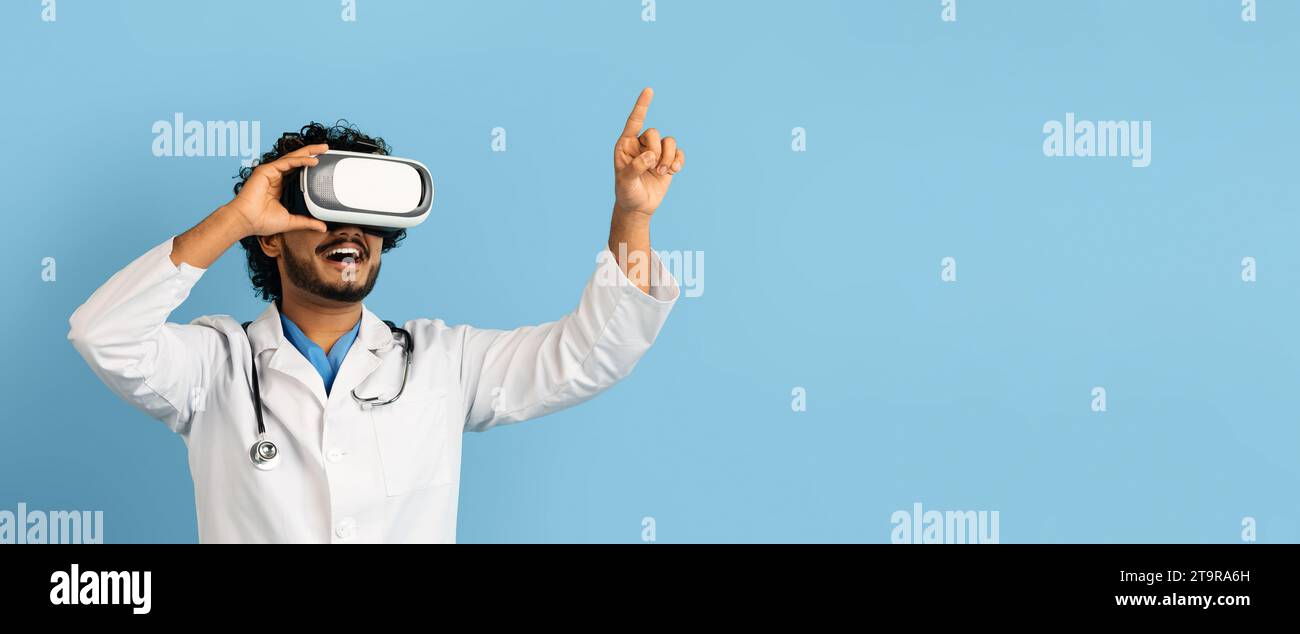 Indian doctor using wireless VR goggles, blue background, web-banner Stock Photo