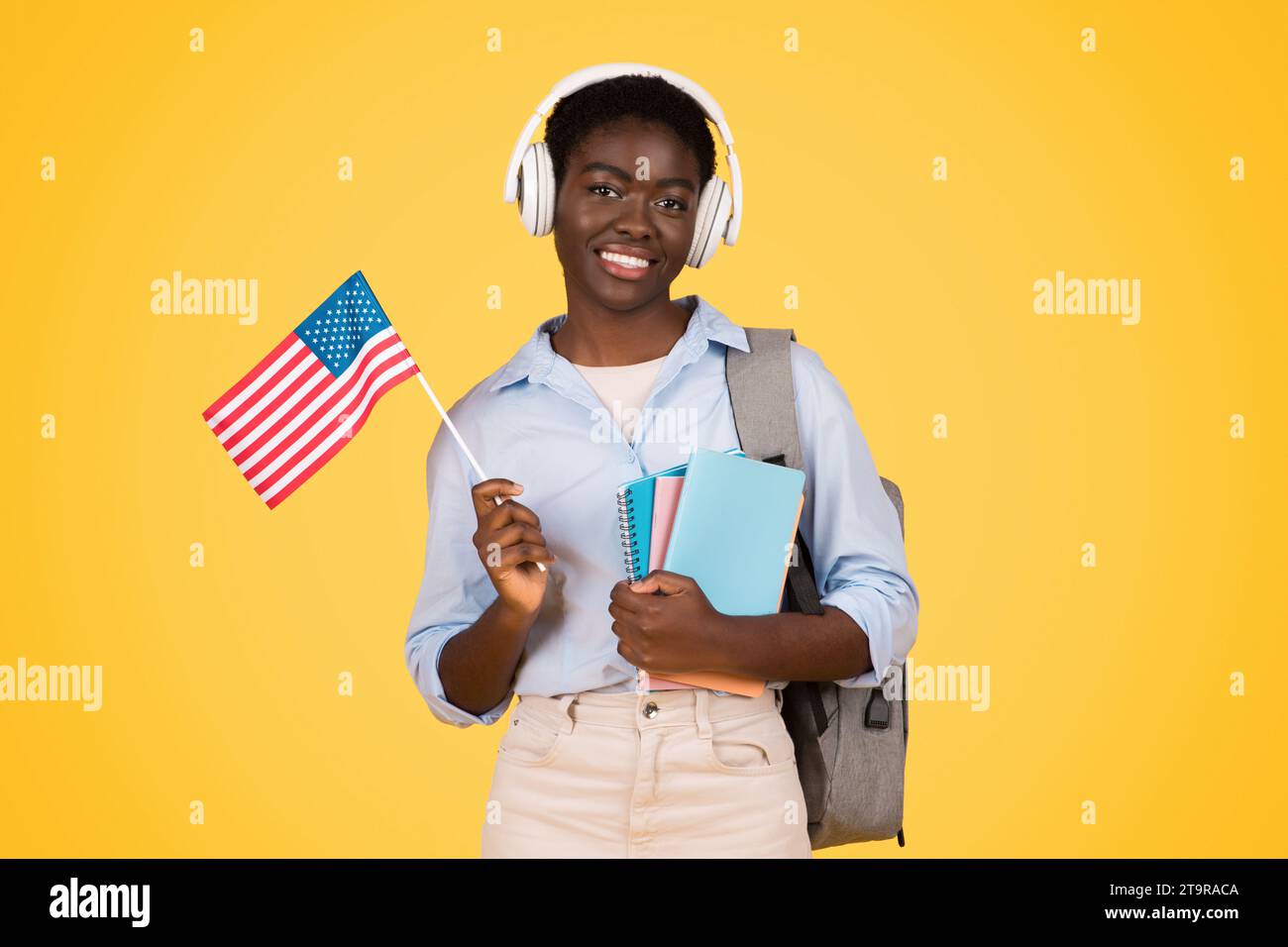 Happy young african american woman student in wireless headphones, with ...