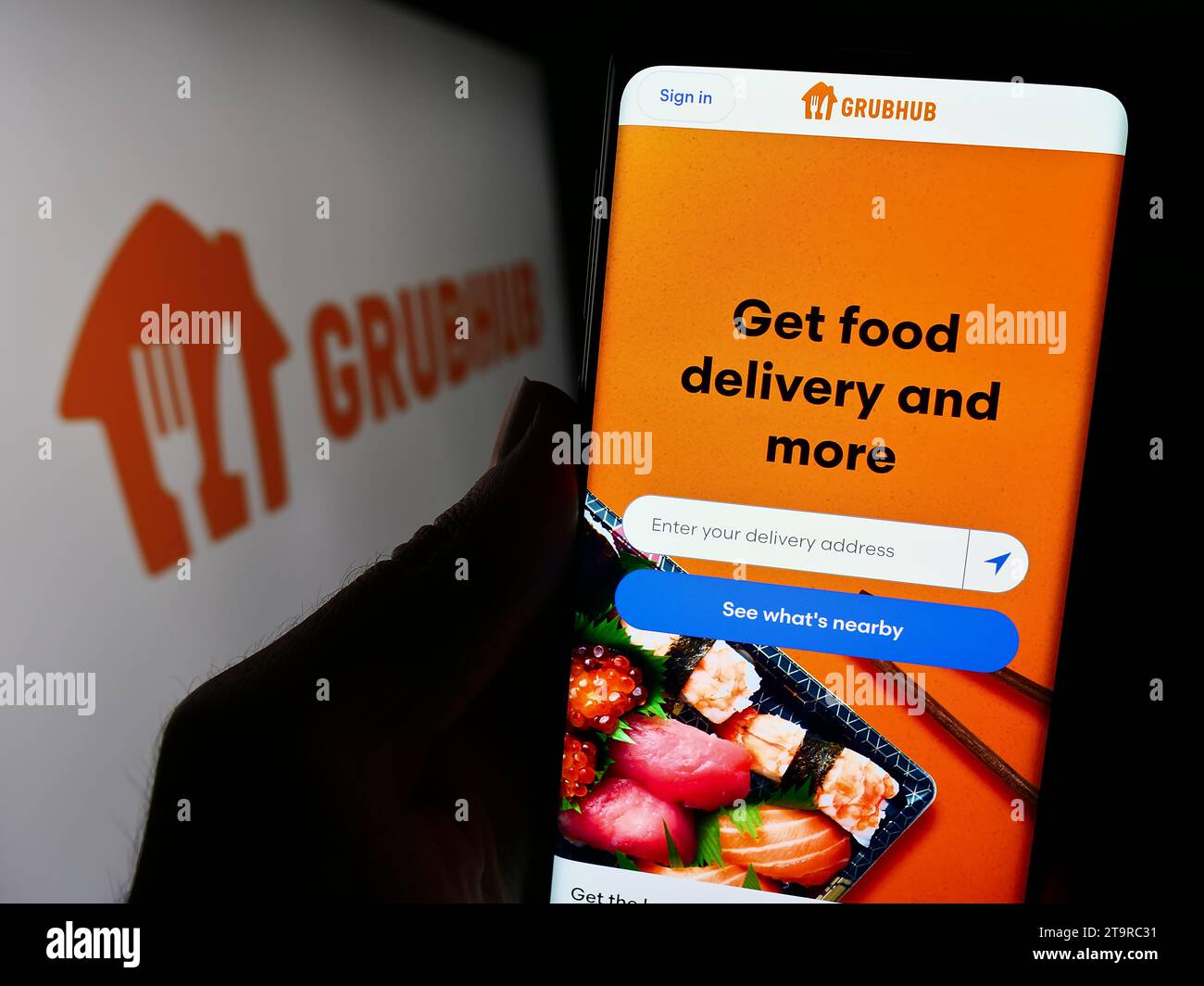 Person holding cellphone with webpage of US food ordering and delivery company Grubhub Inc. in front of logo. Focus on center of phone display. Stock Photo