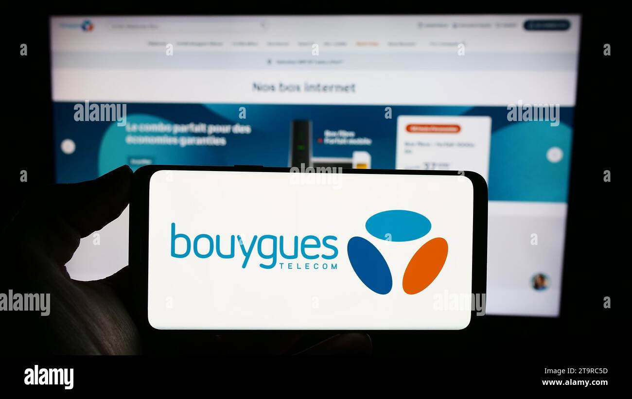 Person holding cellphone with logo of French telecommunications company Bouygues Telecom SA in front of business webpage. Focus on phone display. Stock Photo