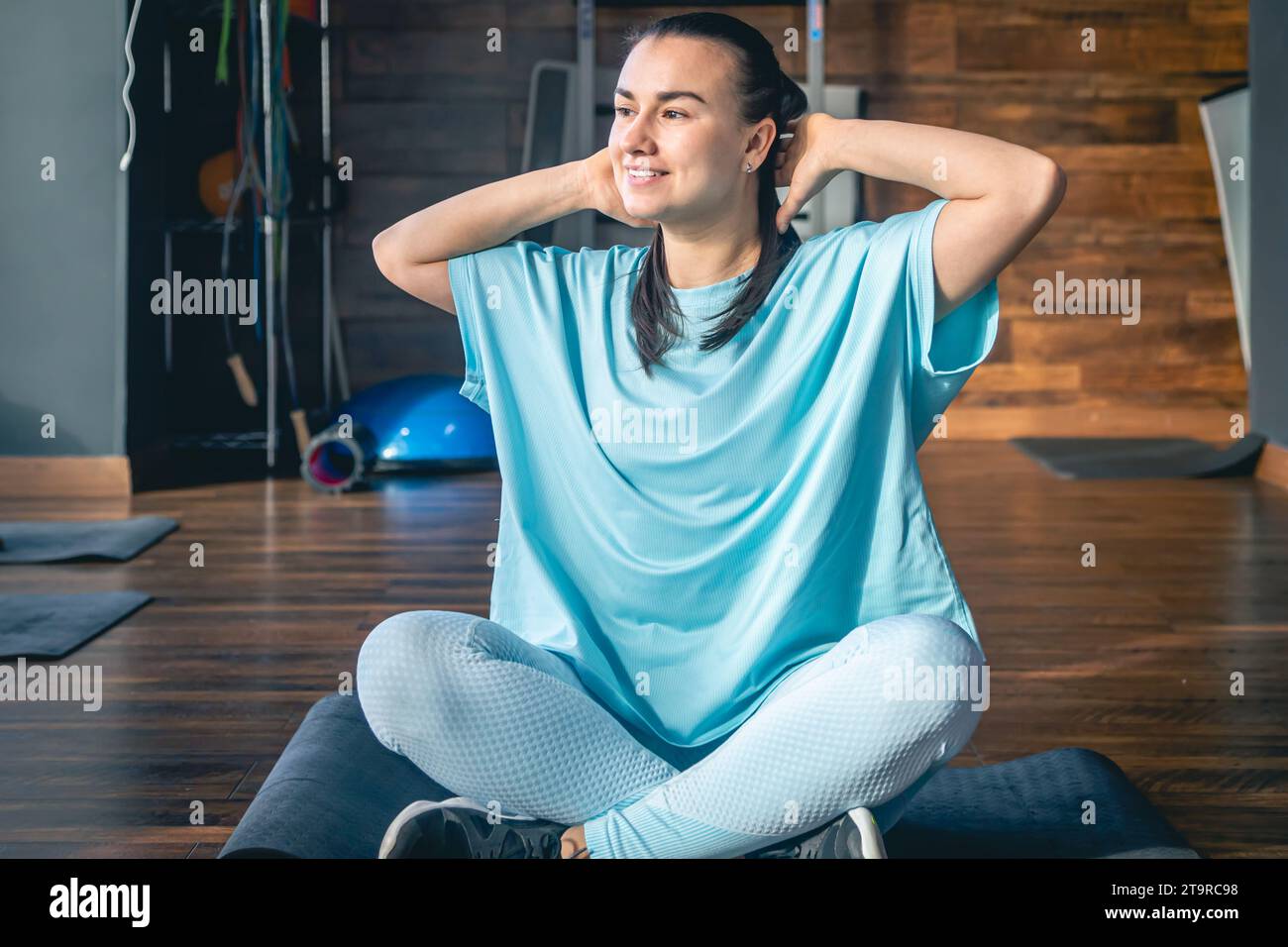 Young woman sitting on a mat in a fitness center, doing yoga and ...