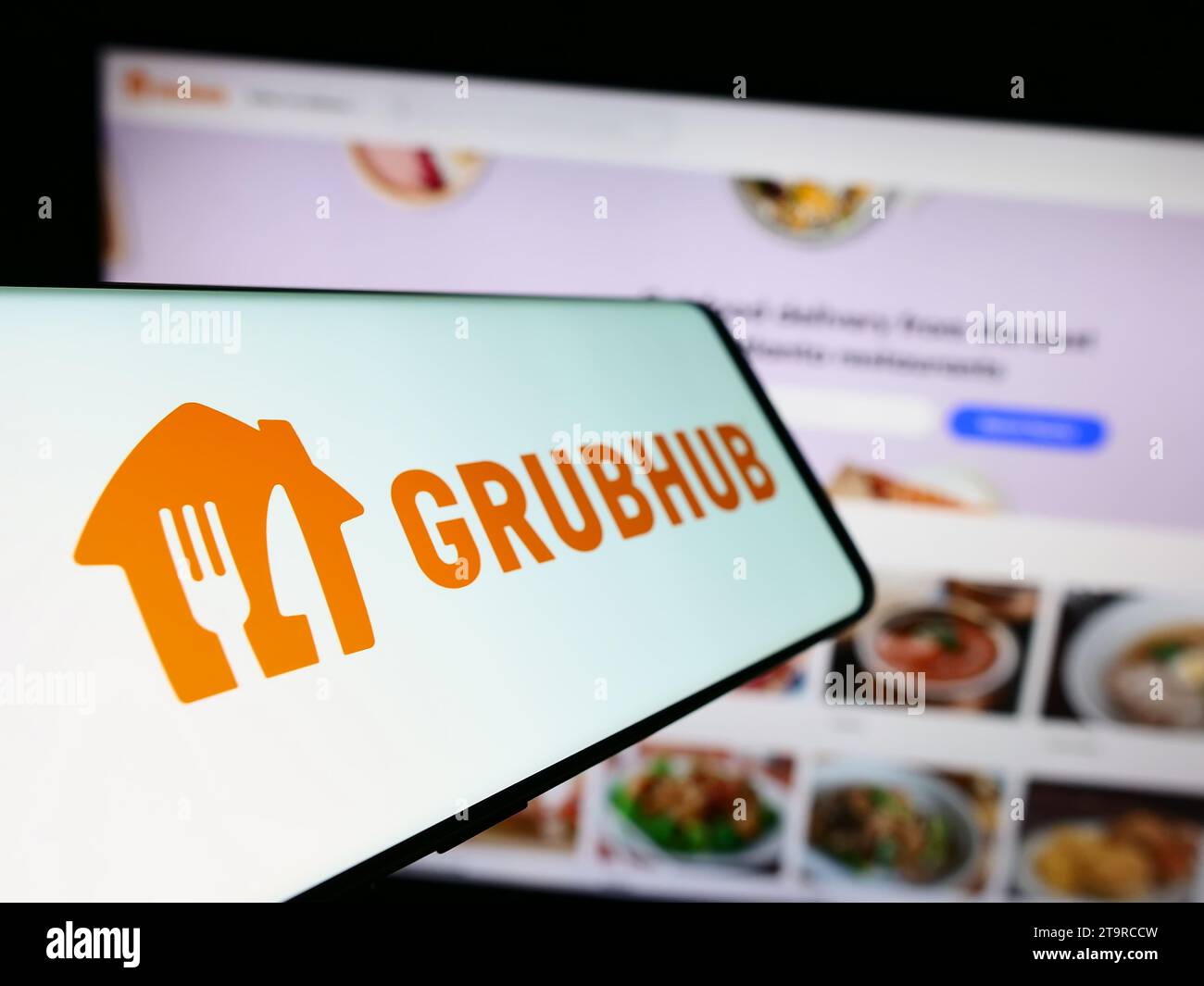 Mobile phone with logo of American food ordering and delivery company Grubhub Inc. in front of website. Focus on center-left of phone display. Stock Photo