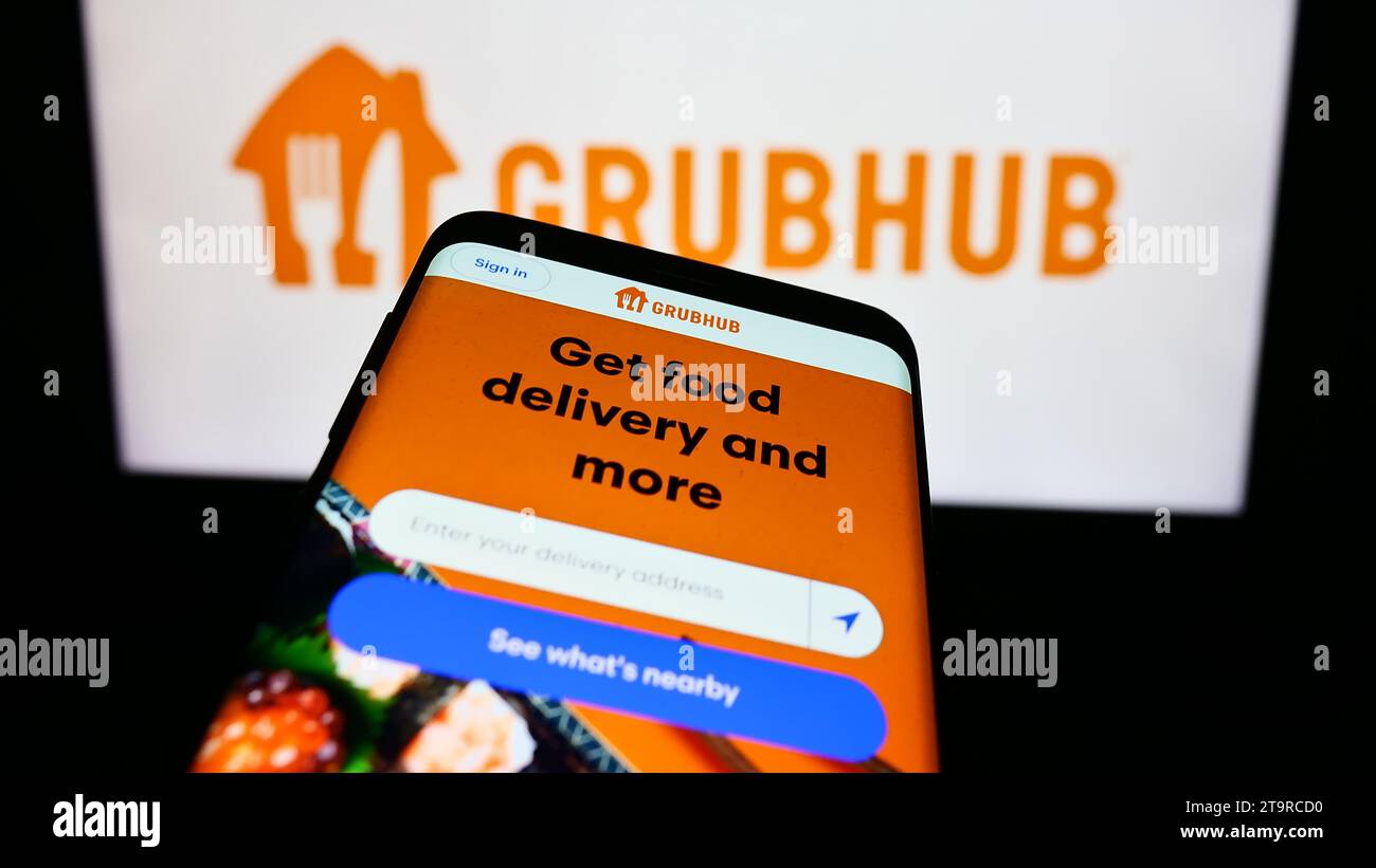 Smartphone with website of US food ordering and delivery company Grubhub Inc. in front of business logo. Focus on top-left of phone display. Stock Photo