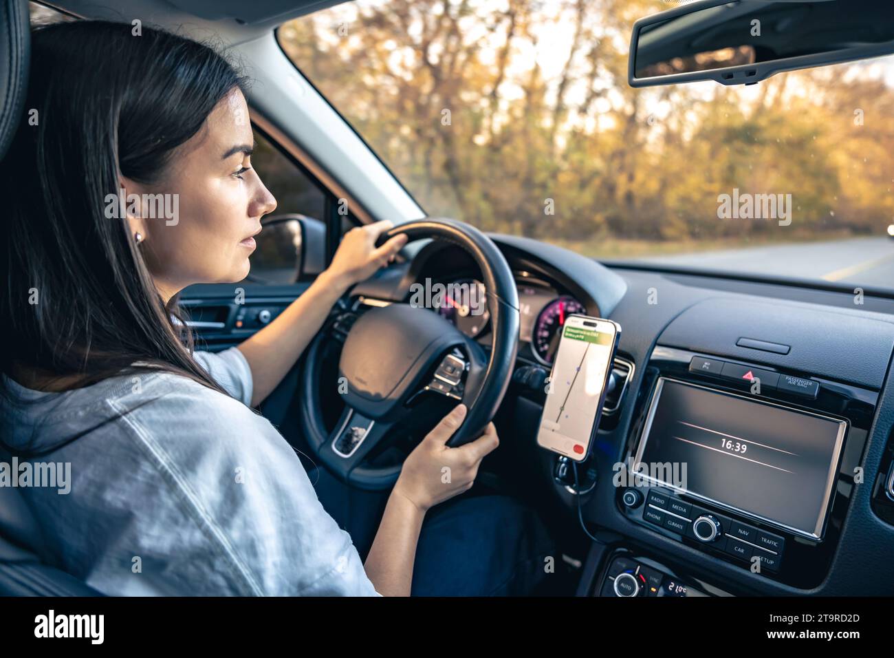 Woman using navigation app on smartphone while driving a car. Stock Photo