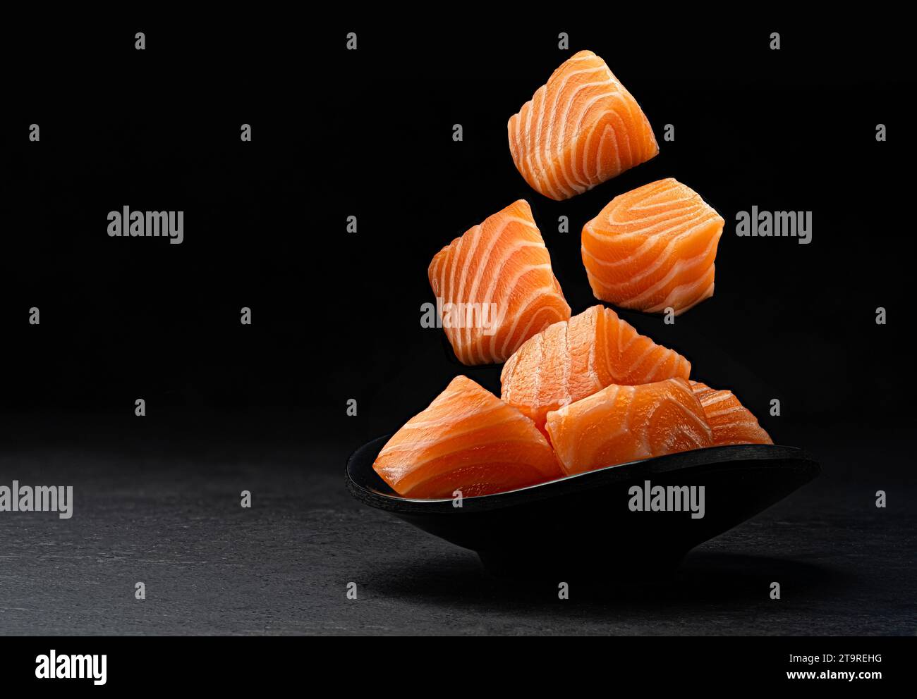 Falling salmon cubes isolated on black background with copy space Stock Photo