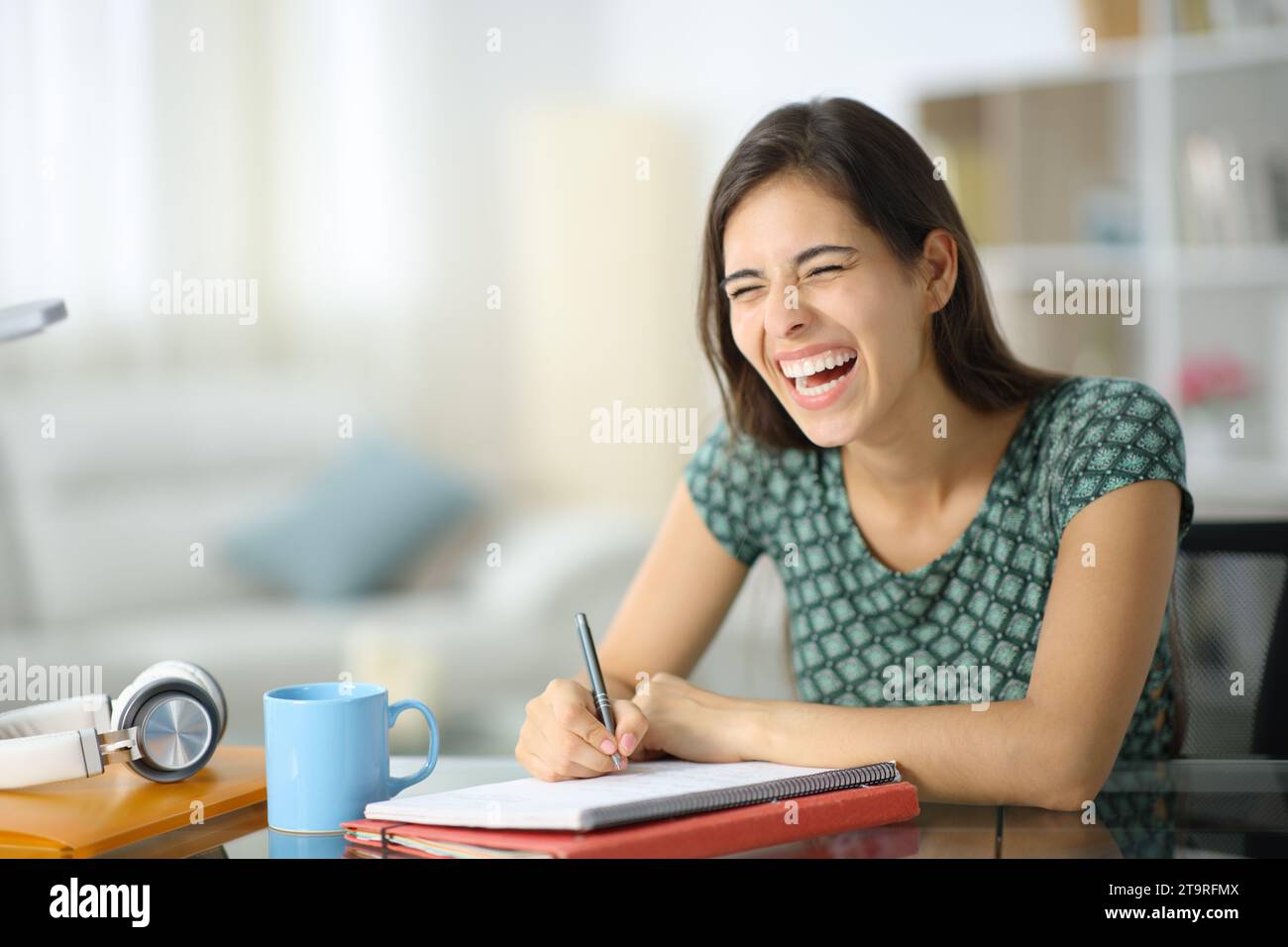 Happy student laughing loud studying at home Stock Photo