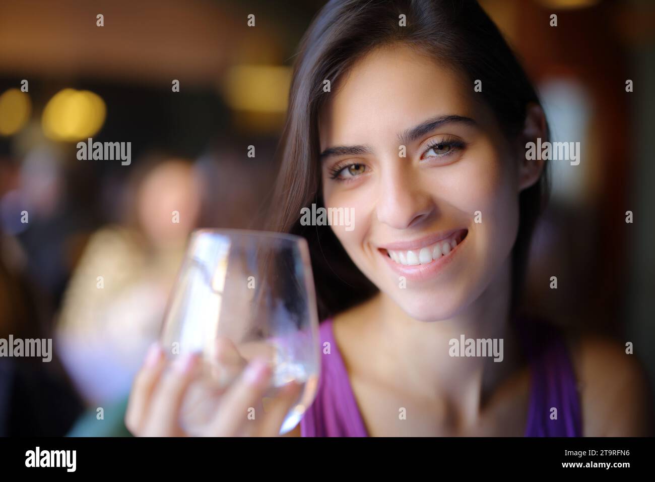 Happy restaurant customer holding water glass looking at camera Stock Photo
