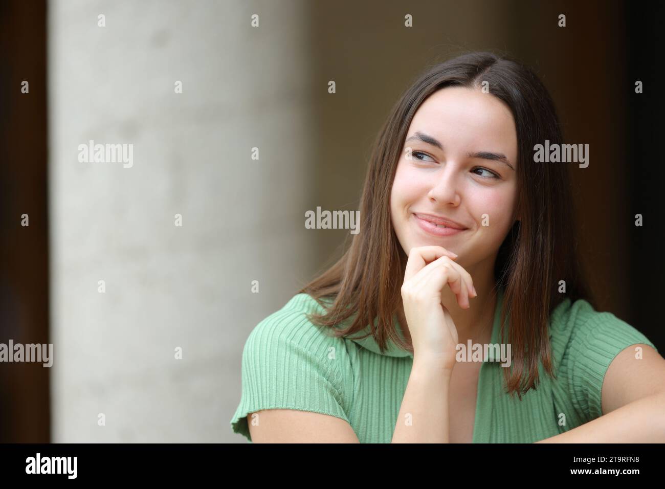 Front view portrait of a satisfied woman wondering looking at side outdoors in the street Stock Photo