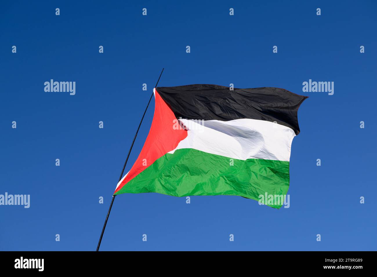 A Palestinian flag against the blue sky at the start of a pro-Palestine march called for a ceasefire of the ongoing military offensive of Gaza by Isra Stock Photo