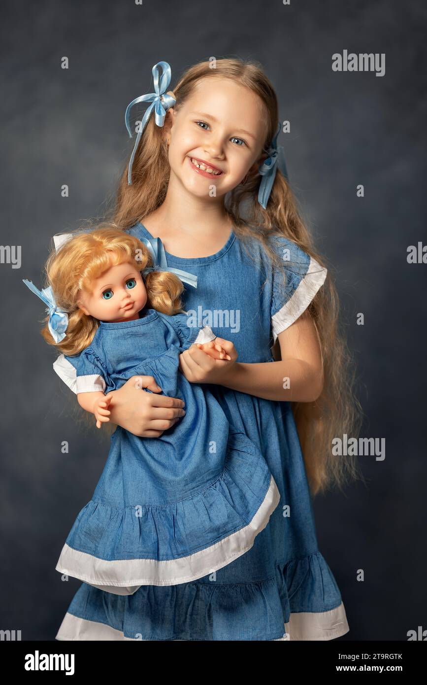 Portrait of ?ute girl child kid and doll isolated on grey background. Child and favorite toy. A gift for a birthday or other holiday. Stock Photo