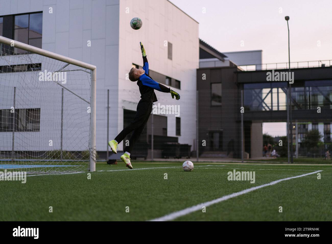 Kids playing football, boy goalkeeper catches ball in goal. Stock Photo