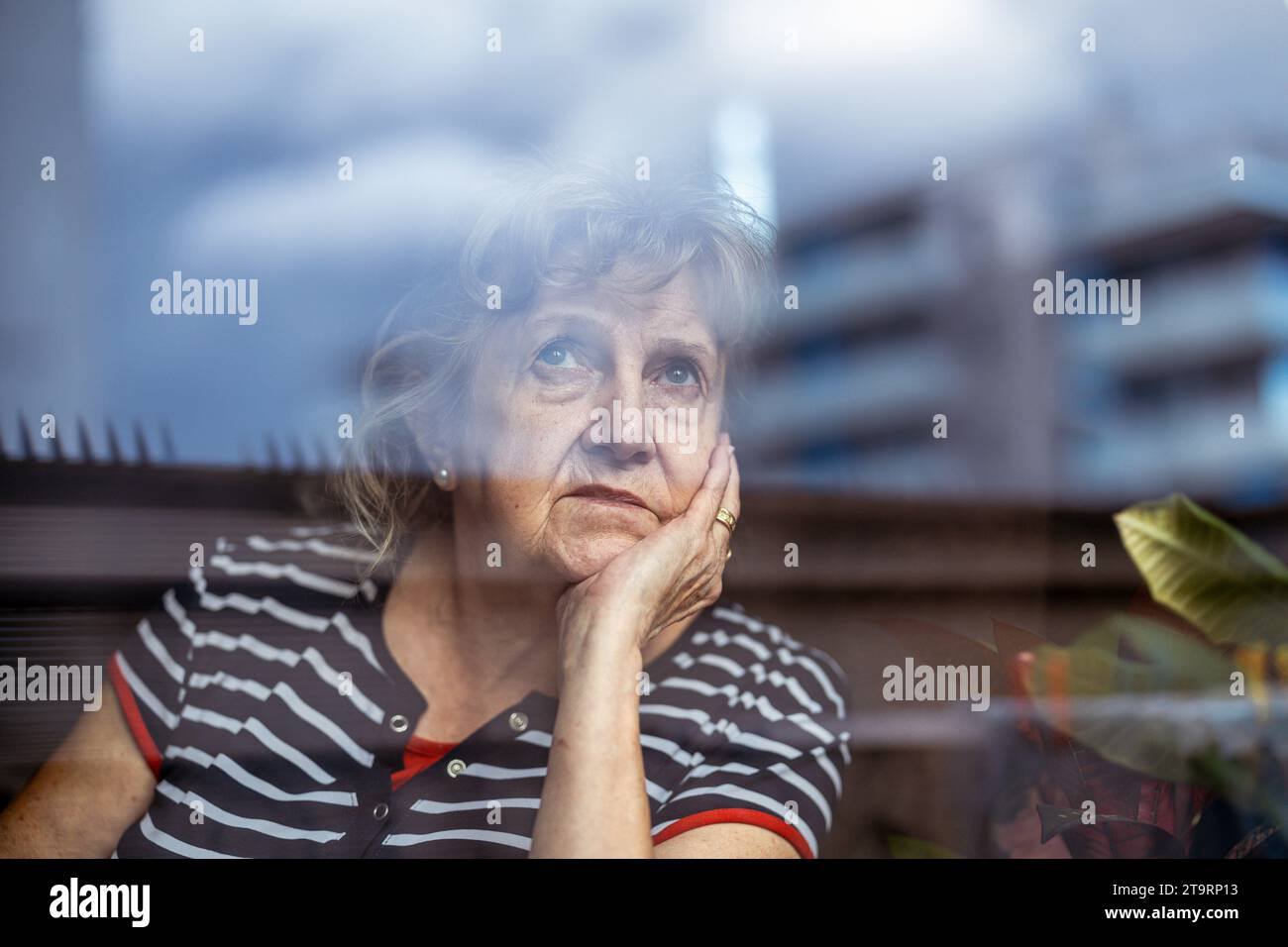 Portrait of senior woman looking through window Stock Photo