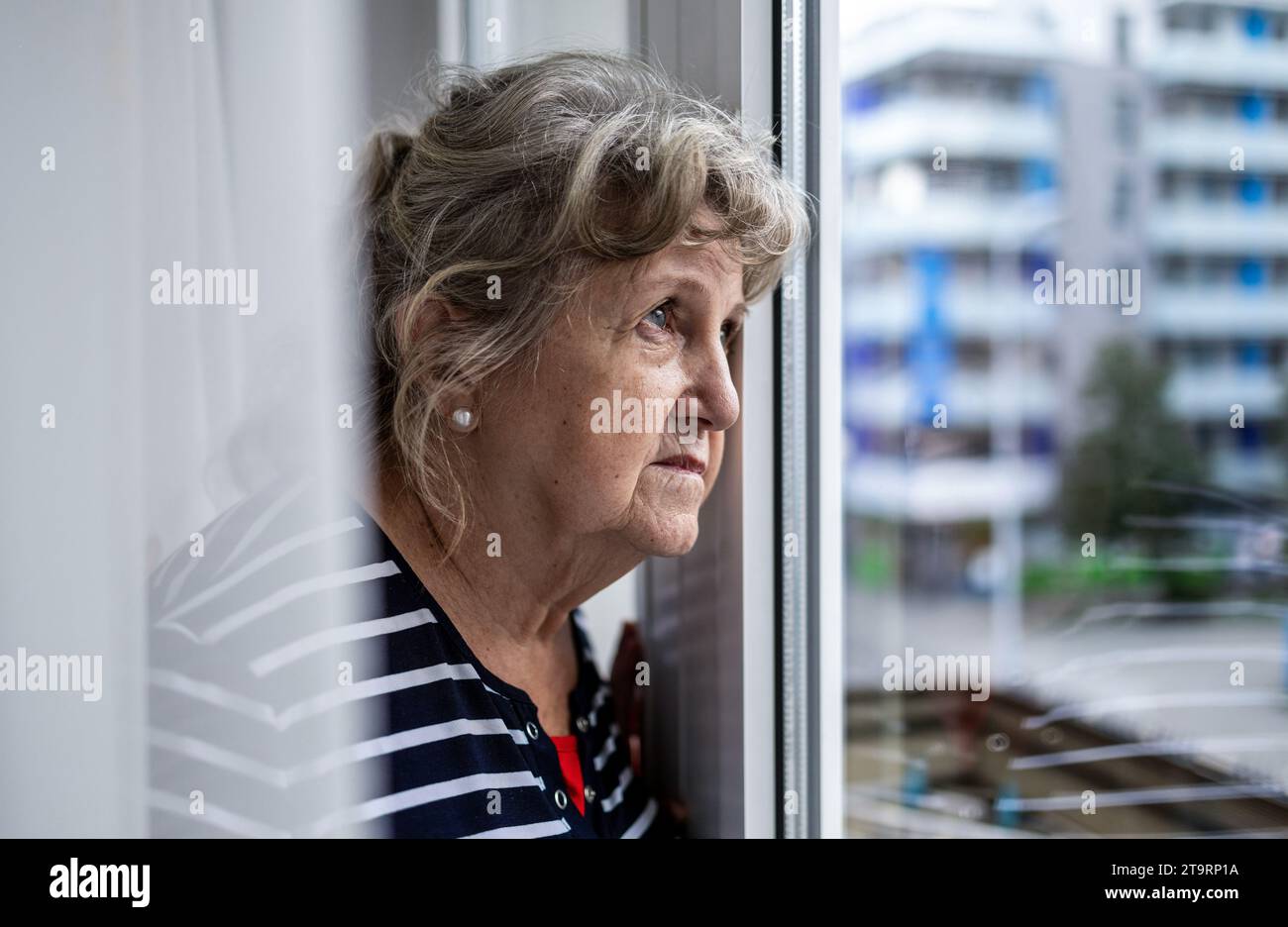 Portrait of senior woman looking through window Stock Photo