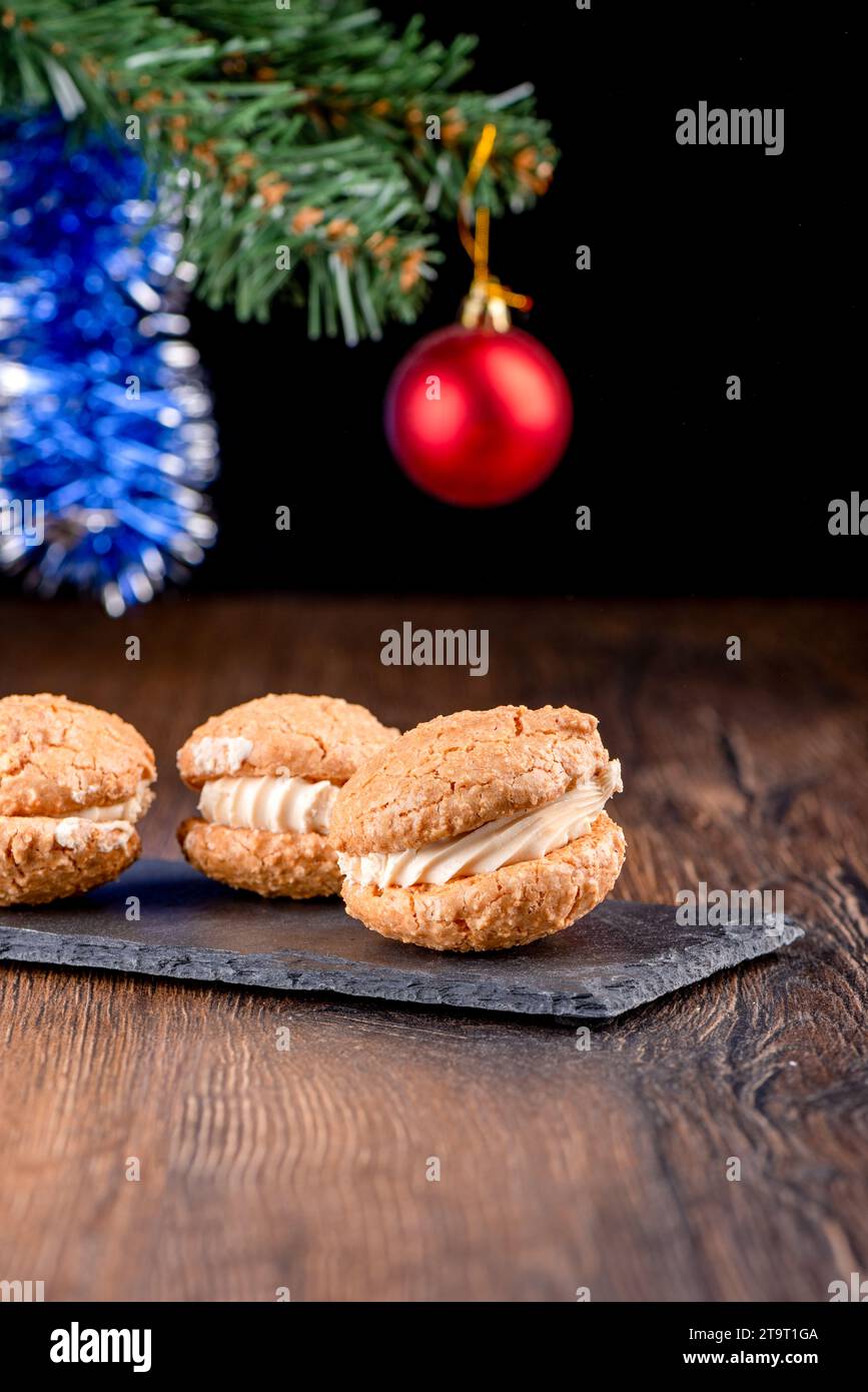 Coconut cookies with cream on a mica serving board and blurred New Year's background. Copy space. Stock Photo