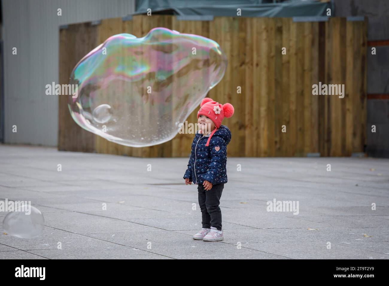 child looking at large soap bubbles near the cathedral, Cologne, Germany.   ###EDITORIAL USE ONLY###    Kind bestaunt grosse Seifenblasen nahe Dom, Ko Stock Photo