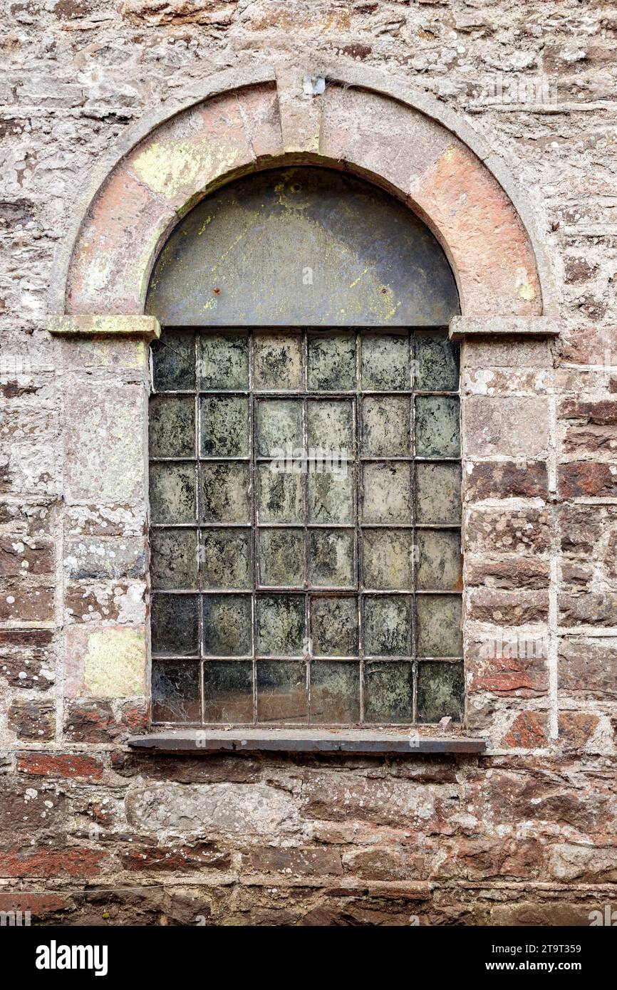 Old arched window set into a stone wall Stock Photo