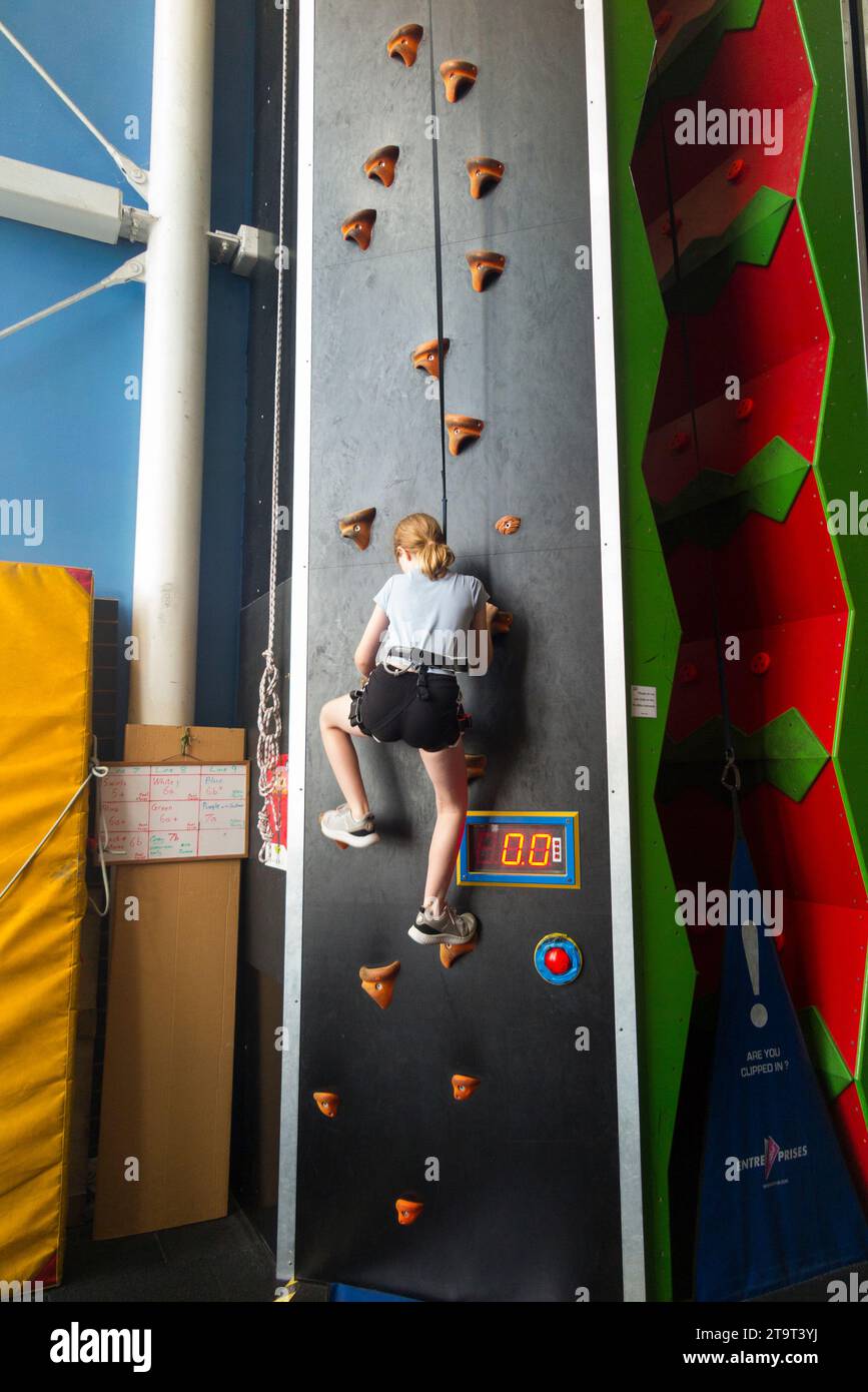 Nine year old girl / age 9 years kid on an indoor climbing wall, with safety rope in case of fall, at a sports' centre. UK. (136) Stock Photo