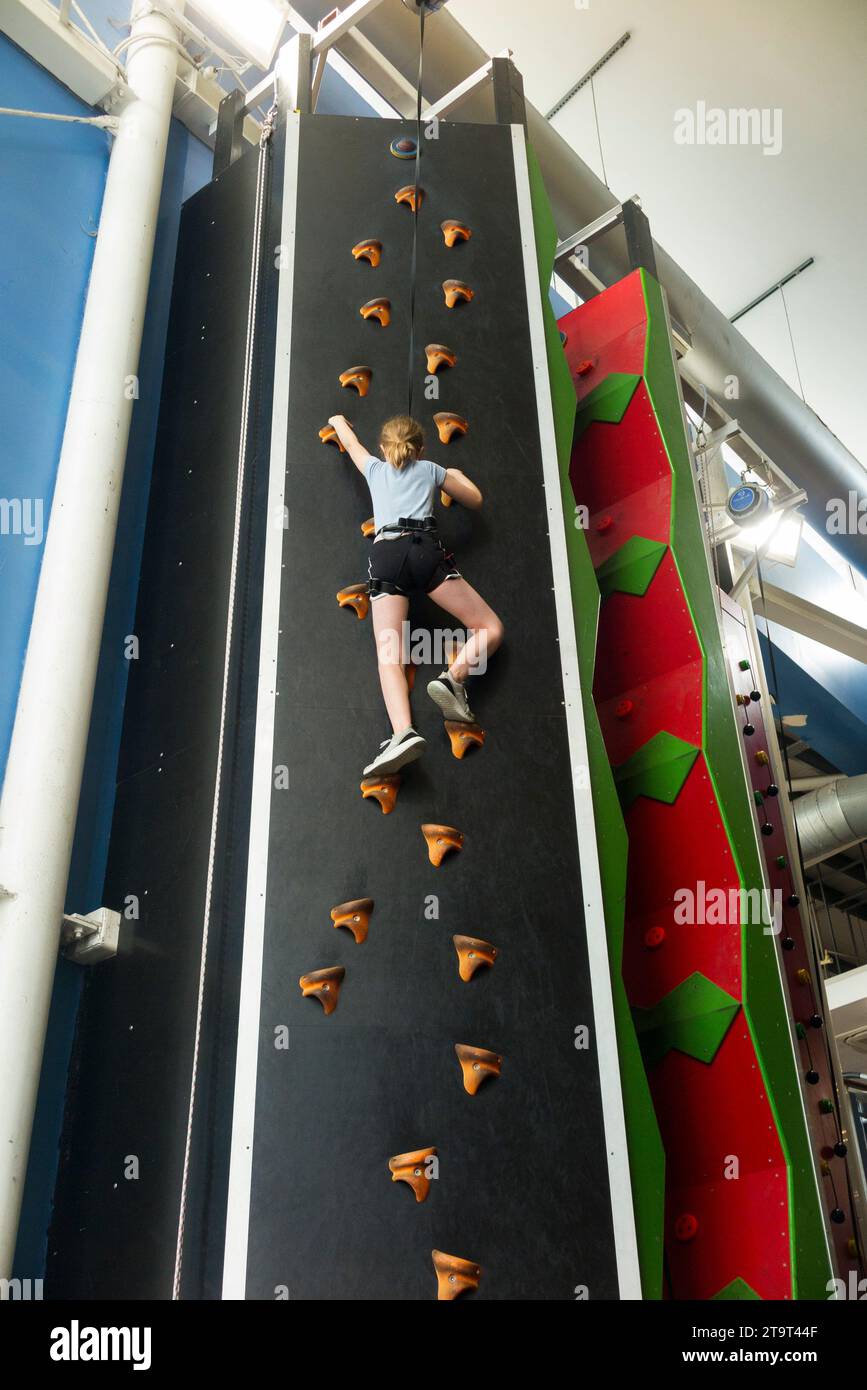 Nine year old girl / age 9 years kid on an indoor climbing wall, with safety rope in case of fall, at a sports' centre. UK. (136) Stock Photo