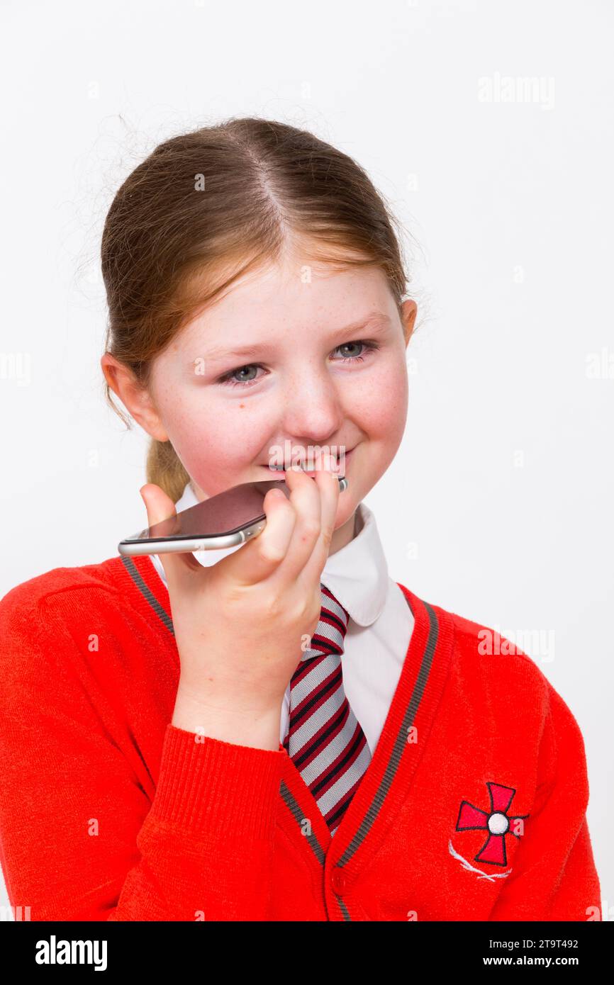 Year 5 school girl child aged 9 years / year old kid wearing school uniform & apple iphone mobile smart telephone device to make phone call. UK. (136) Stock Photo
