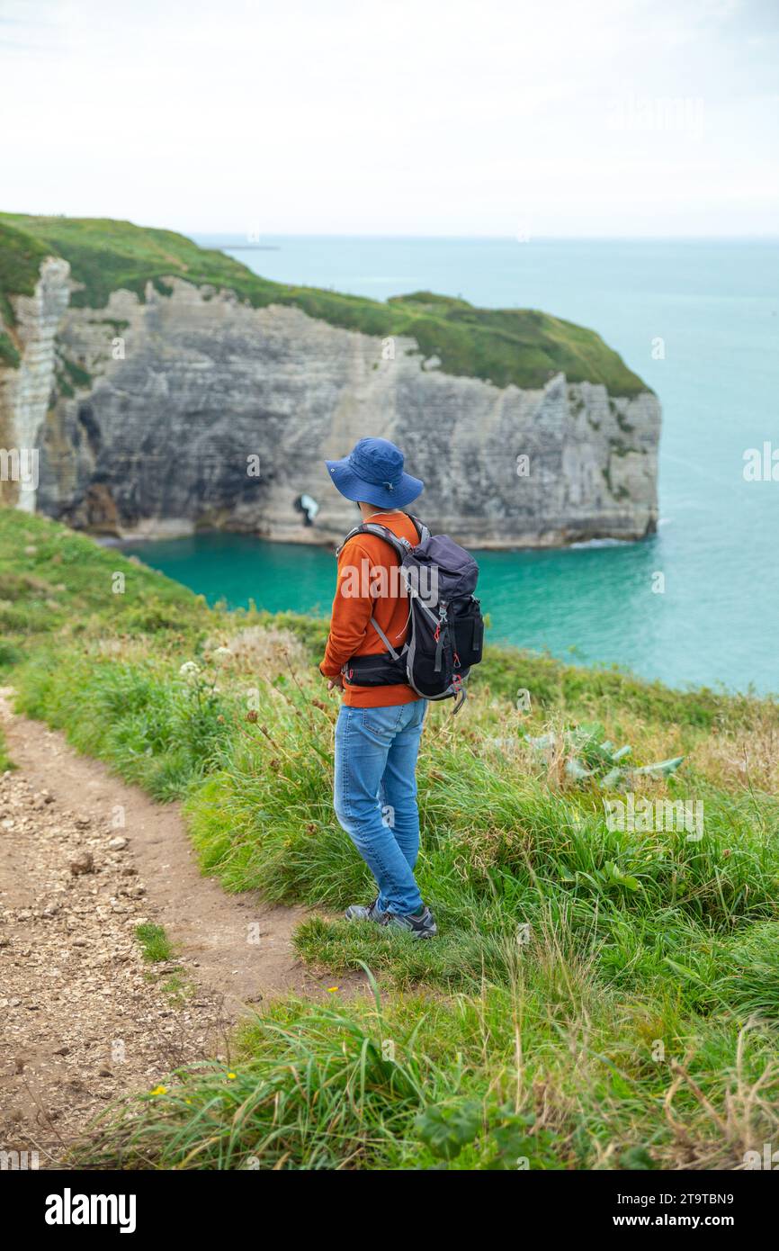 An asian man with backpack walking on the cliff trail in Estretat, France Stock Photo