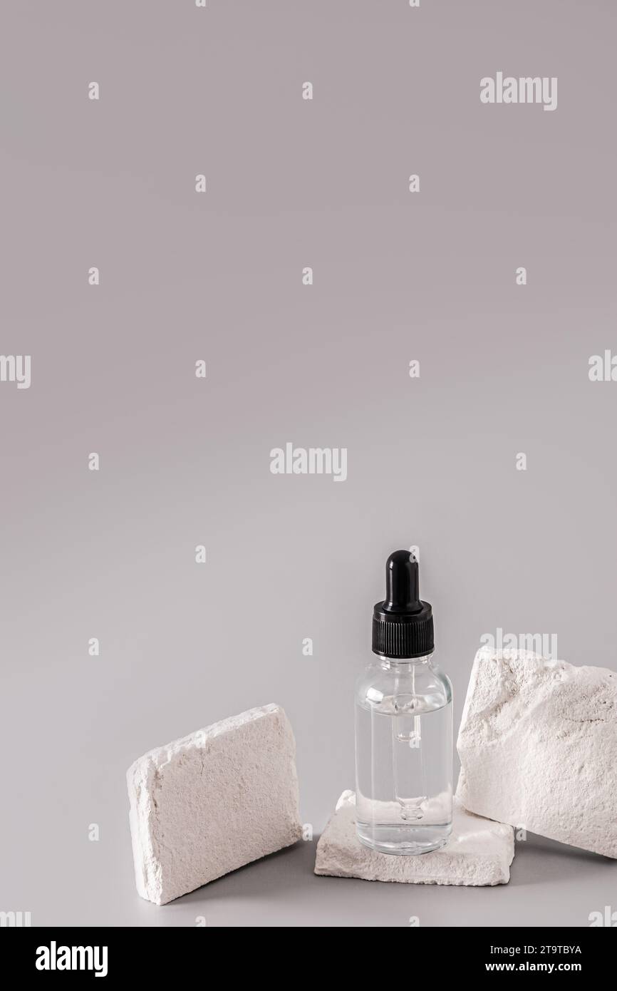 A transparent cosmetic bottle with a dropper with a natural product for the care of sensitive facial skin. Lifting effect. Bleaching. vertical view Stock Photo