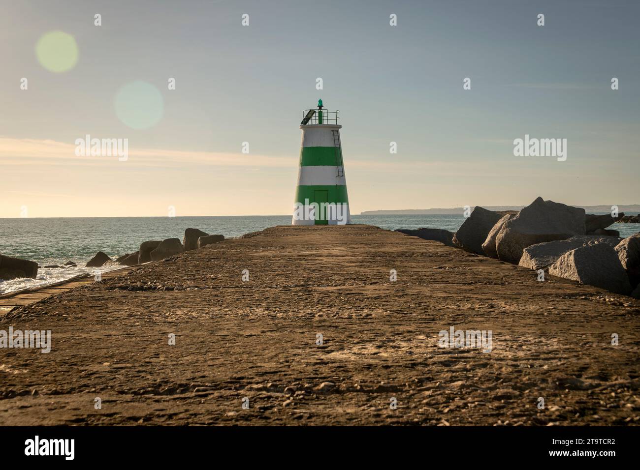 Green and white lighthouse at the end of a causeway at the entrance to Portimao harbour in the Algarve, Portugal. Stock Photo