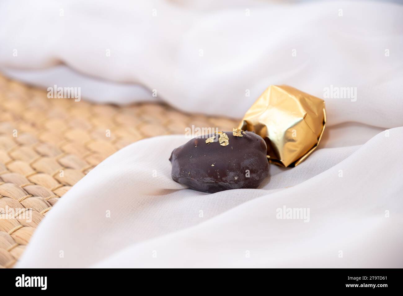 Golden Necklace and Chocolate Pieces on White Background with Elegant Mock-Up Space. Luxury Concept for Jewelry and Chocolates. Perfect for Celebratio Stock Photo
