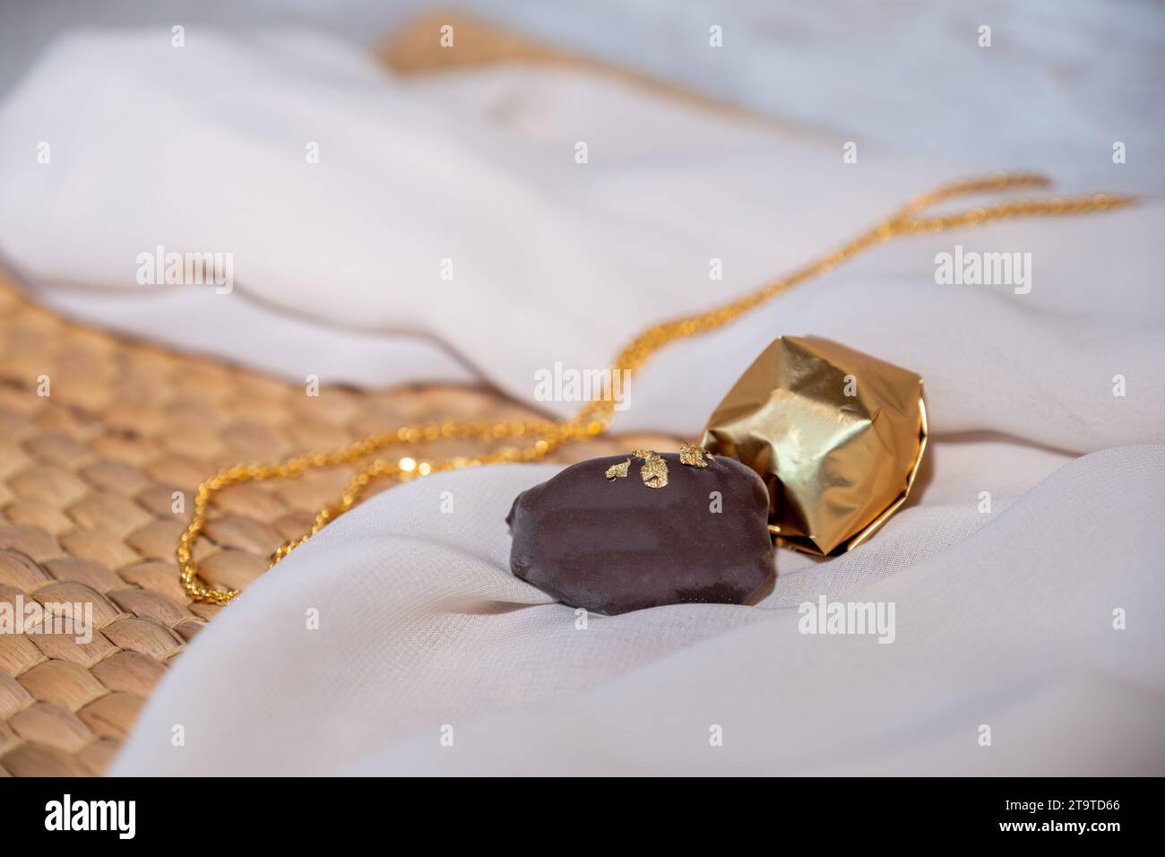 Golden Necklace and Chocolate Pieces on White Background with Elegant Mock-Up Space. Luxury Concept for Jewelry and Chocolates. Perfect for Celebratio Stock Photo