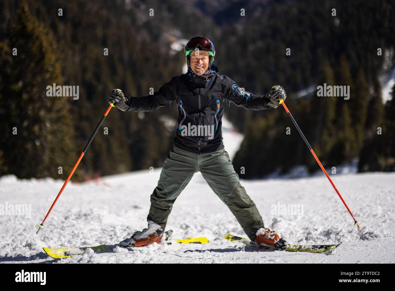 Adult skier standing on slopes in a mountain ski resort. Man posing ...