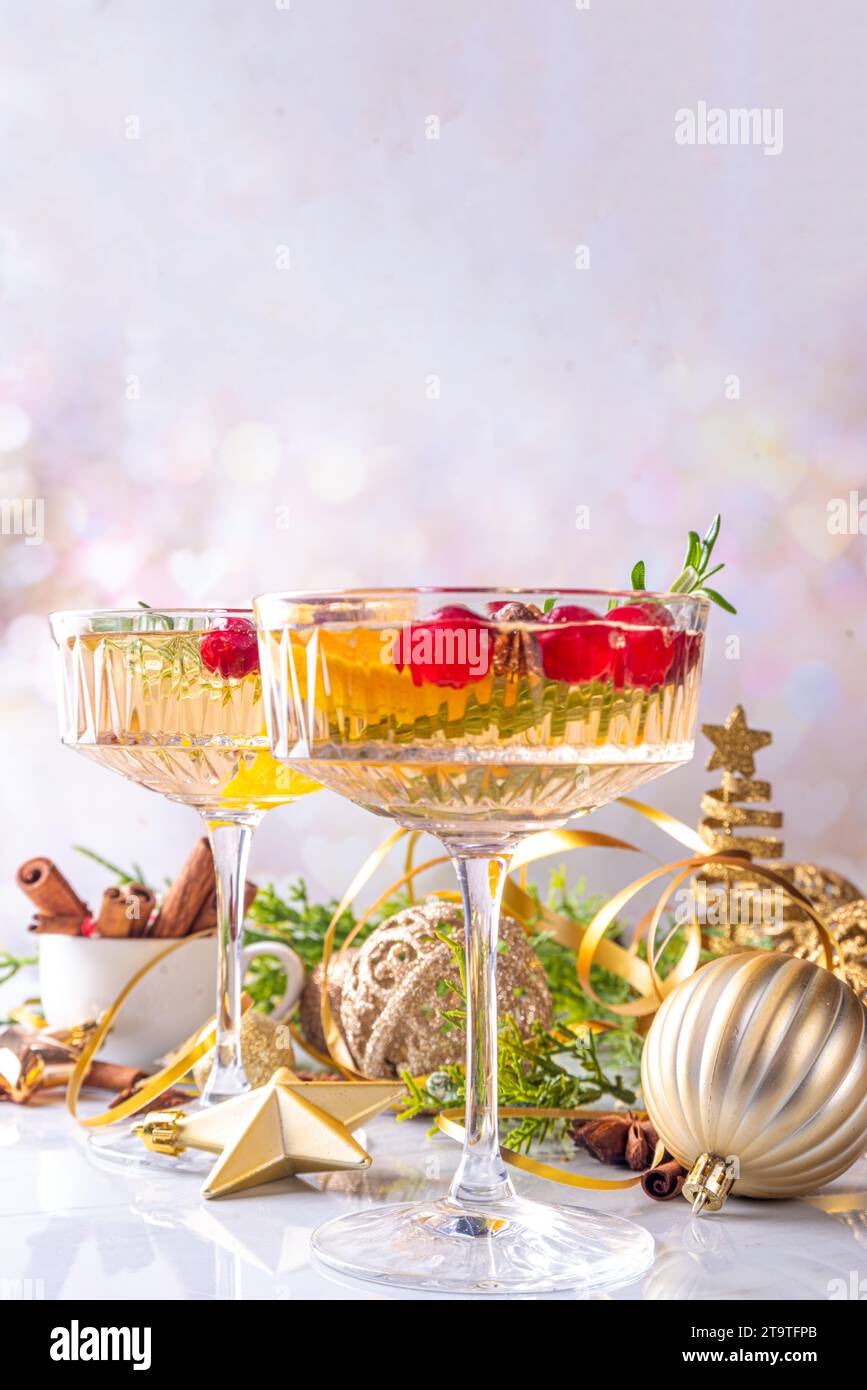 Christmas champagne fruit punch with cranberry, orange, spices and rosemary. Sweet alcohol cocktail glasses, on Christmas and New Year decorated backg Stock Photo