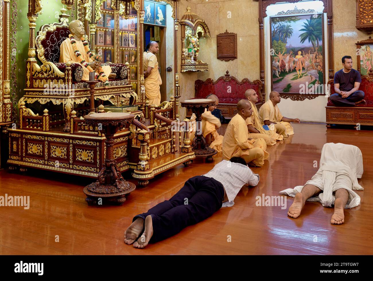 Monks & prostrating lay followers of ISKCON at Sri Sri Radha Gopinath Temple, Mumbai, India, in front of a statue of ISKCON founder Swami Prabhupada Stock Photo