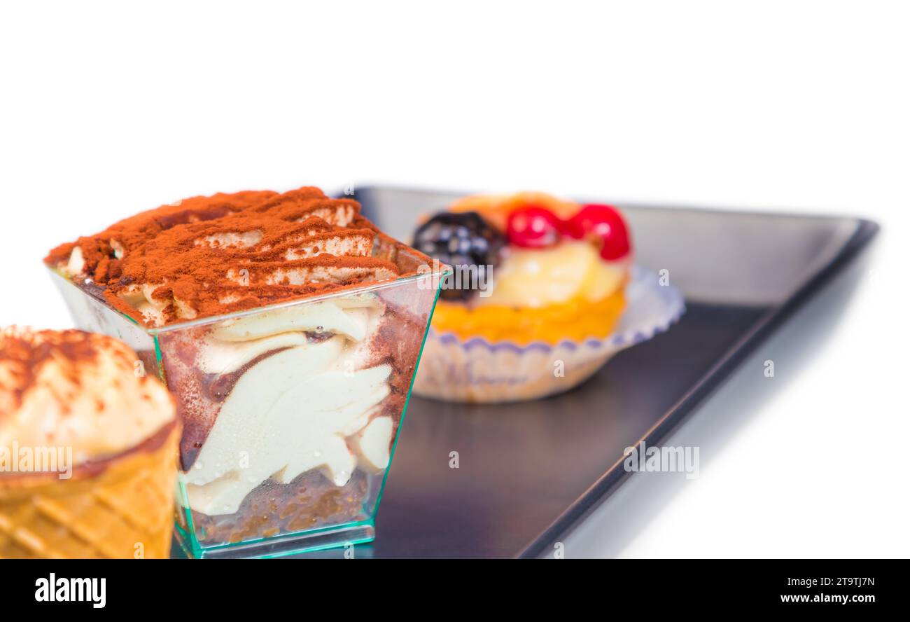 delicious tiramisu cake near little cakes on black dish Stock Photo