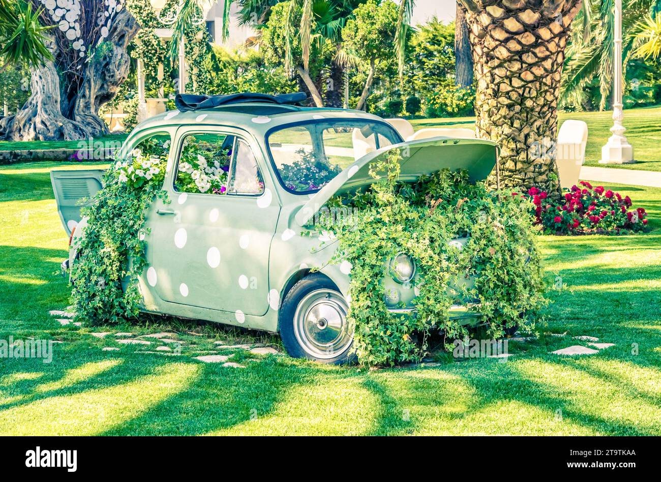 old little wedding car on green garden near flowers and leaves, vintage style Stock Photo