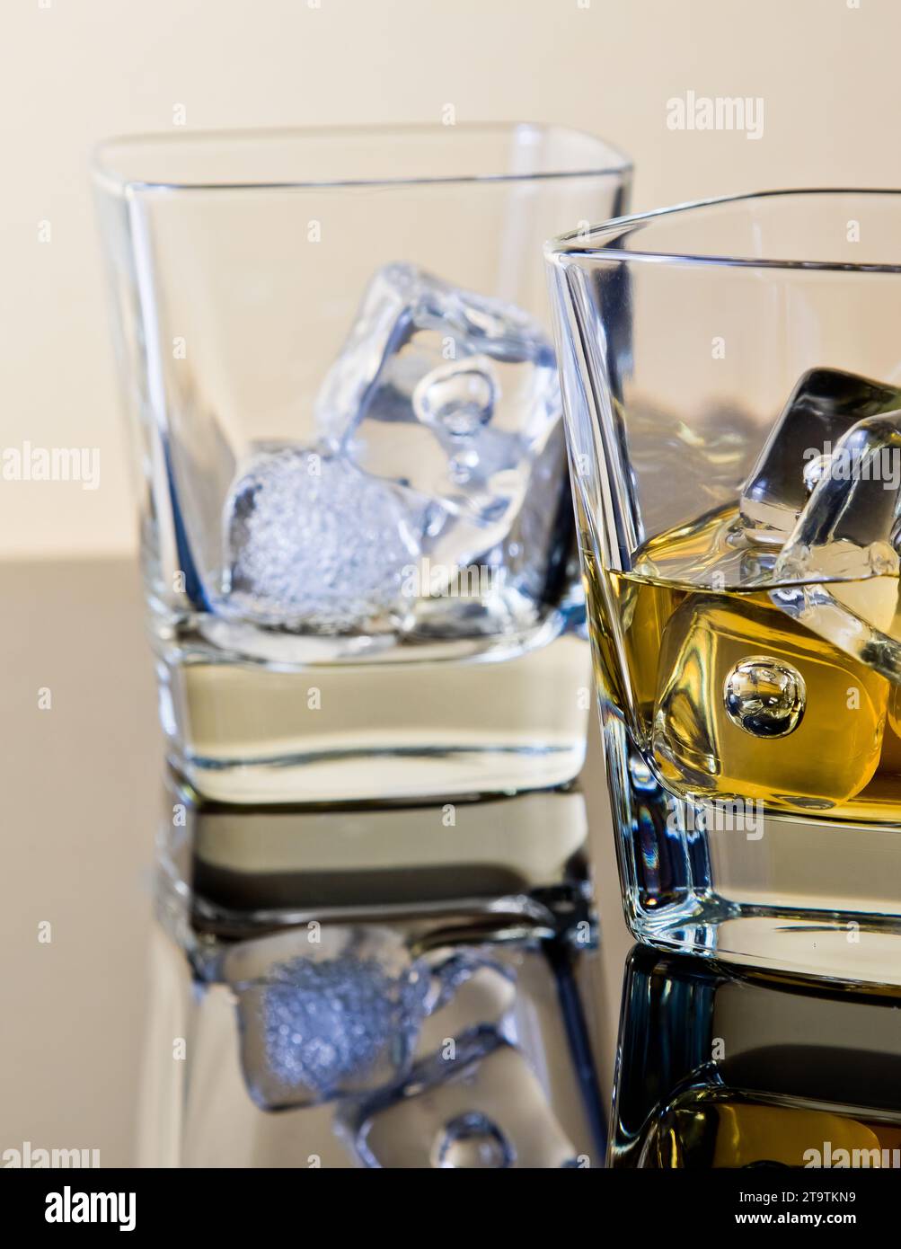 one glass of whiskey and one empty with ice cubes on table with reflection, time of relax with whisky Stock Photo