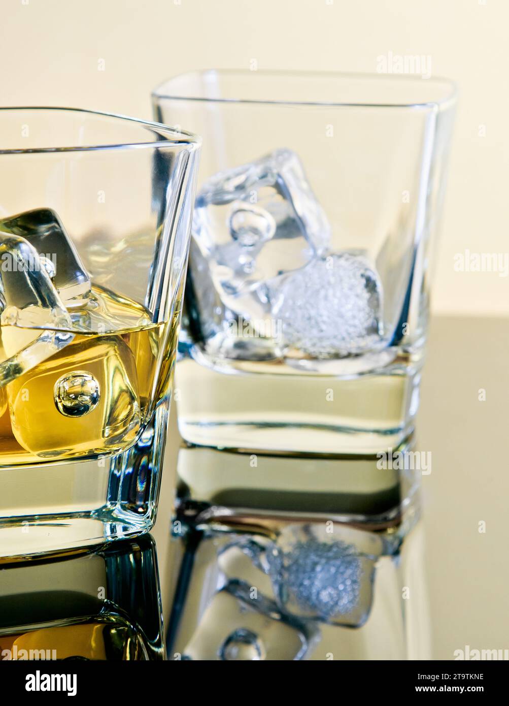 one glass of whiskey and one empty with ice cubes on table with reflection, time of relax with whisky Stock Photo