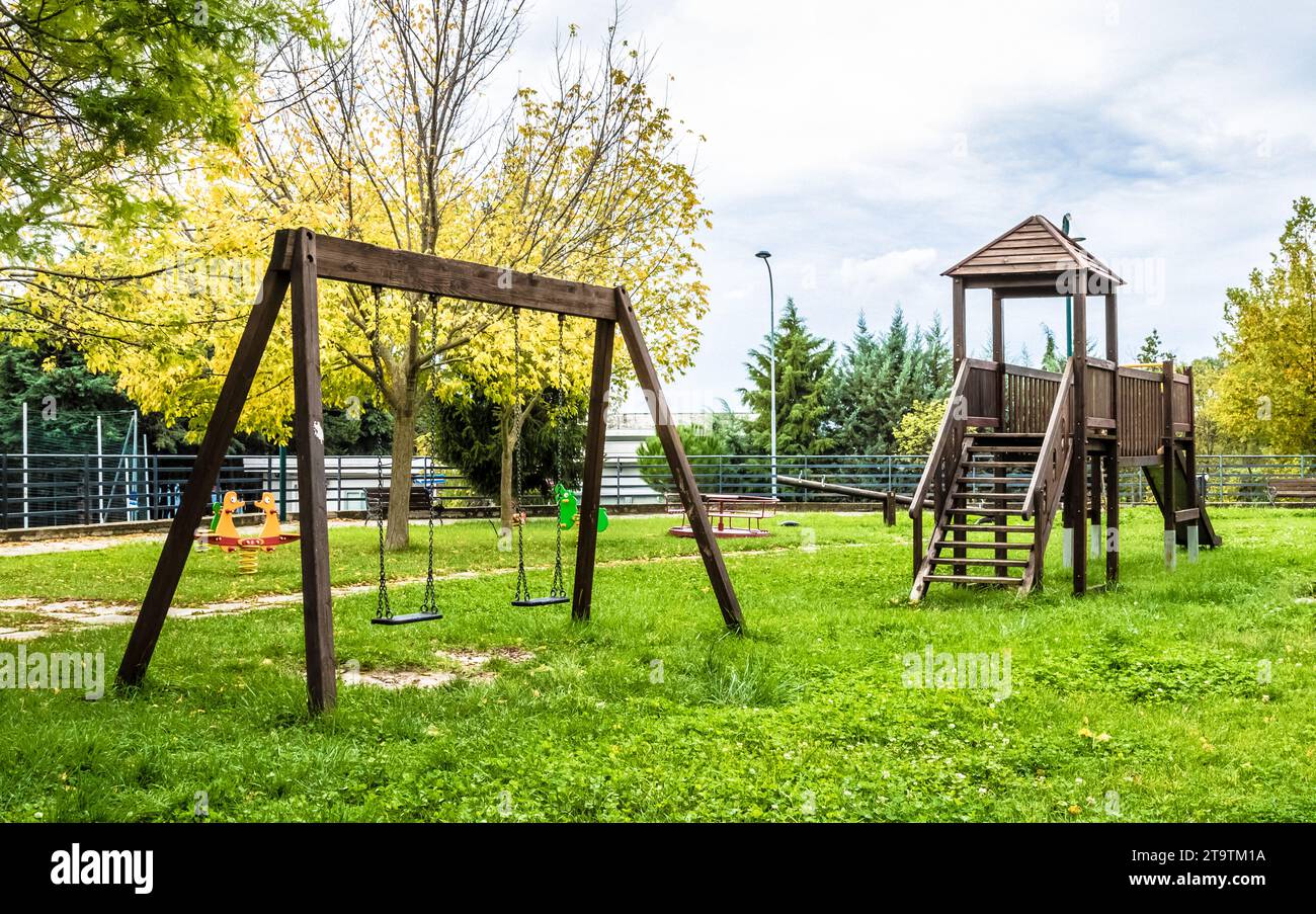 empty swings at playground for child near children stairs slides equipment, on green meadow background Stock Photo