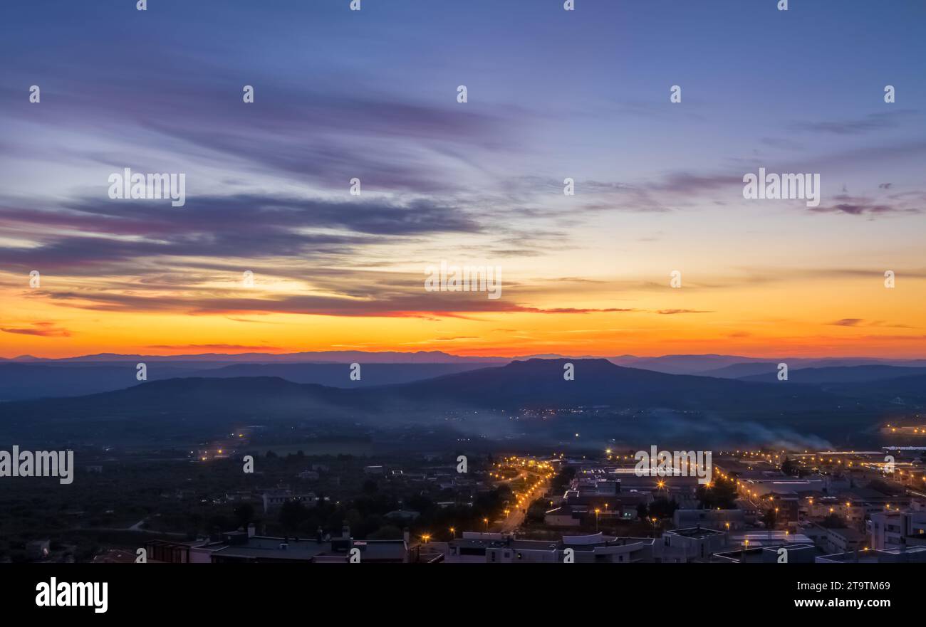 sunset scene with mountains in background, colorful sky with soft clouds and city Matera in foreground, industrial view Stock Photo