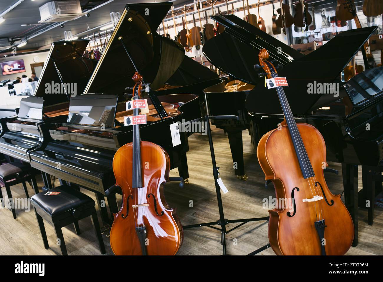 Interior of a music shop with various instruments including a concert grand pianos and cellos Stock Photo