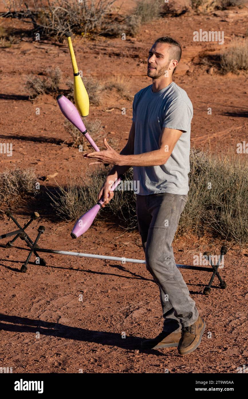 A participant in the GGBY Highlining Festival practices his juggling while not walking the highlines.  Moab, Utah. Stock Photo