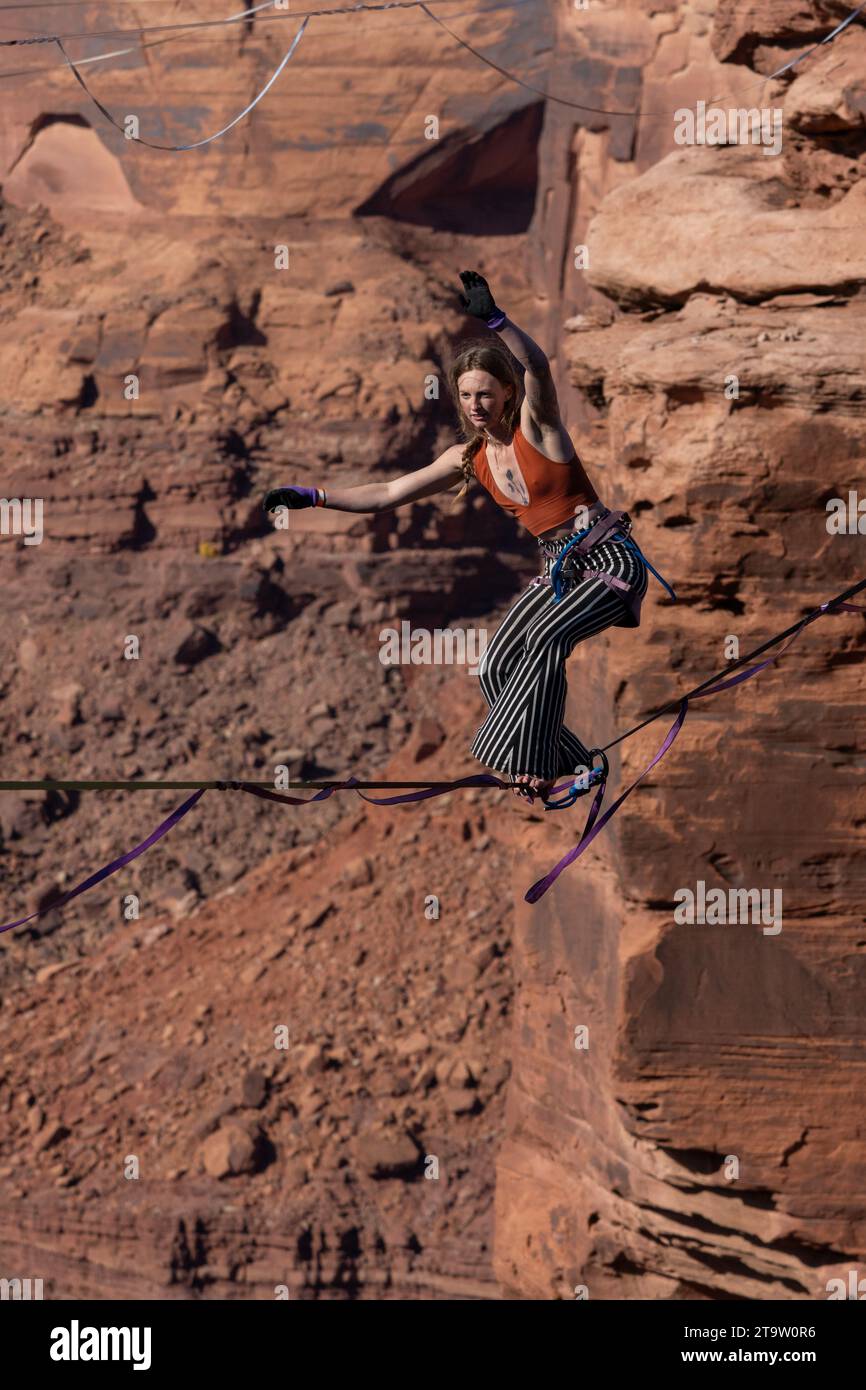 A young woman walking a highline at the GGBY World Highline Festival in Mineral Canyon near Moab, Utah. Stock Photo