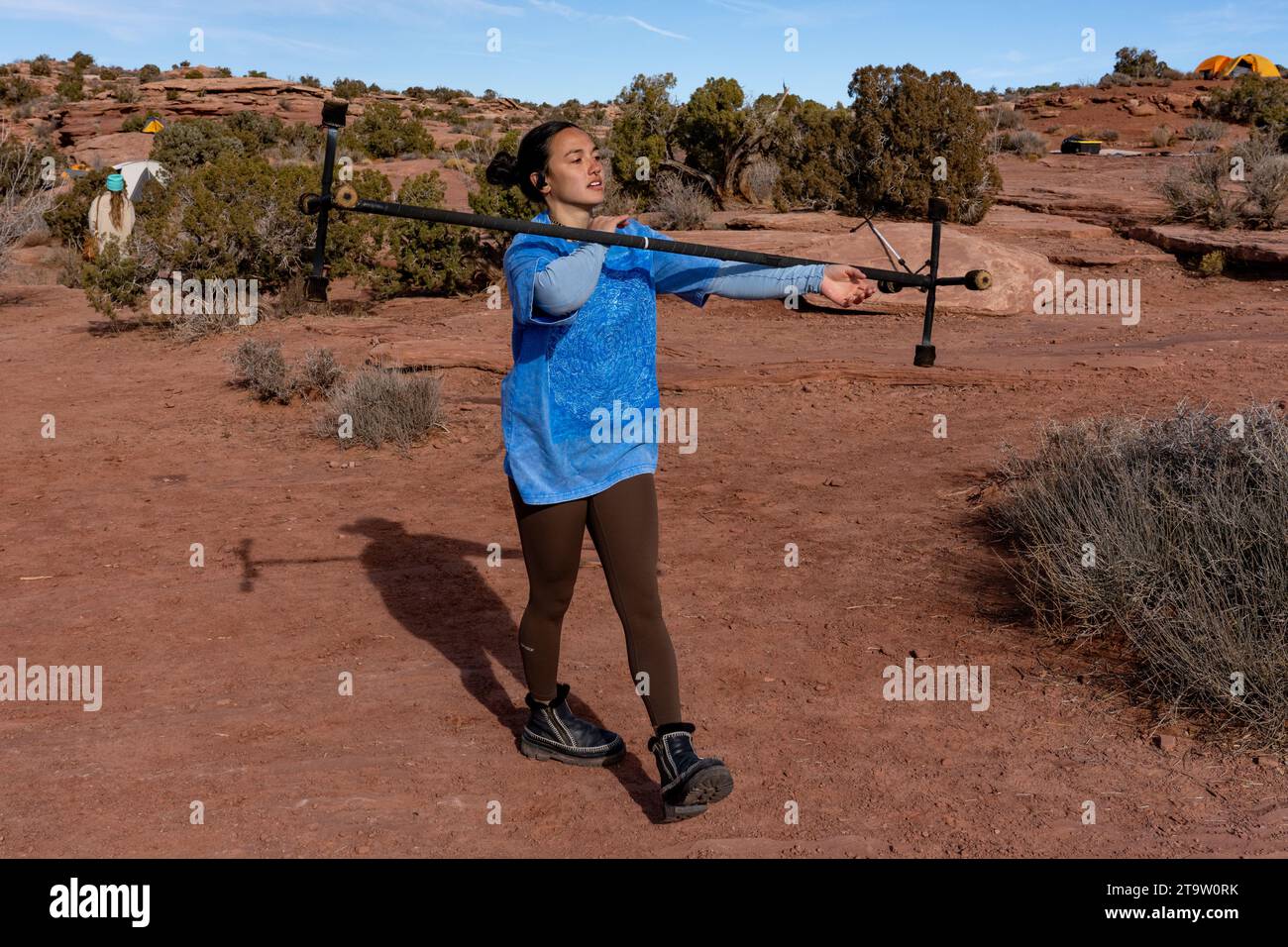 A young woman practices with a fire dragon staff at the GGBY Highlining Festival in Moab,  Utah.  She is rolling the staff down her arms.  Usually per Stock Photo
