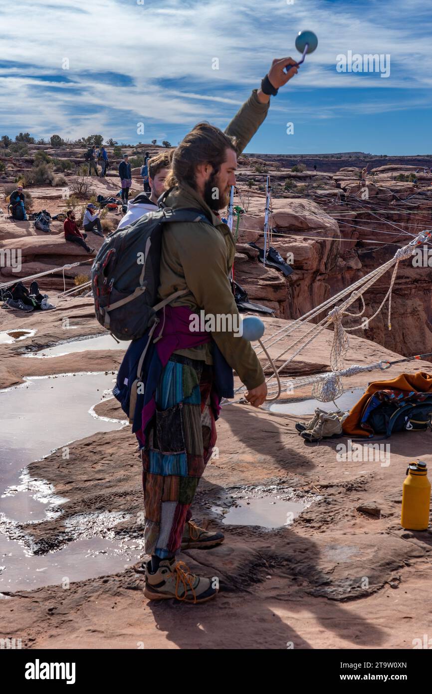 A male participant in the GGBY World Highline Festival practices poi spinning when not walking the highlines.  Moab, Utah. Stock Photo