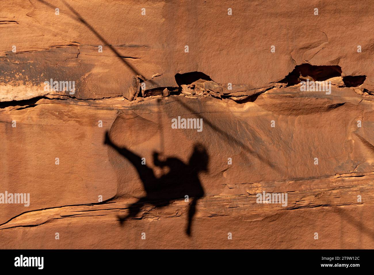 Shadow of a highliner falling off the highline on the canyon wall 500 feet above the canyon floor at a highline festival in Utah. Stock Photo