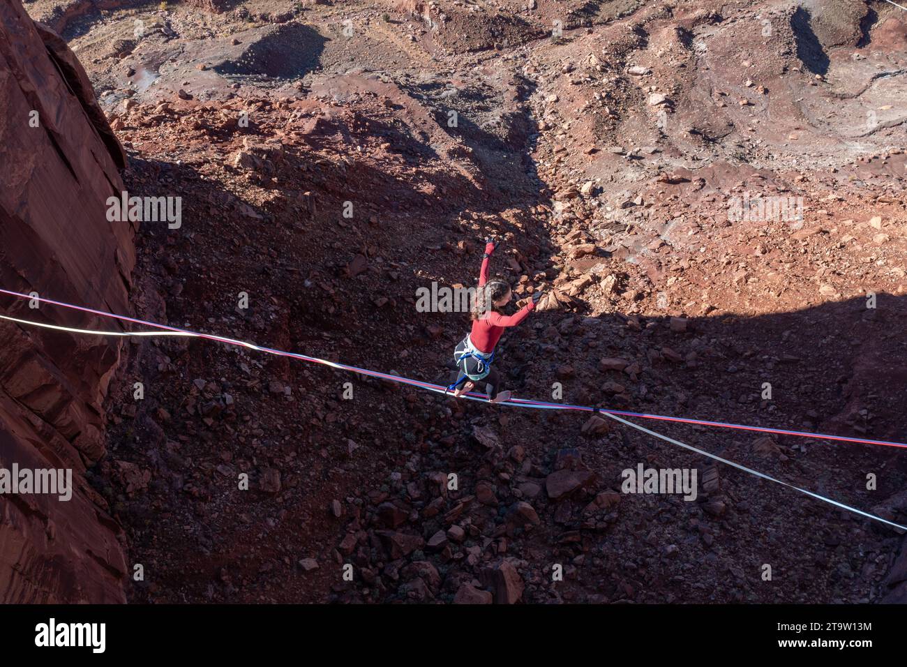 Aerial view of a young woman highlining 500 feet above the canyon floor at the GGBY Highline Festival near Moab, Utah. Stock Photo