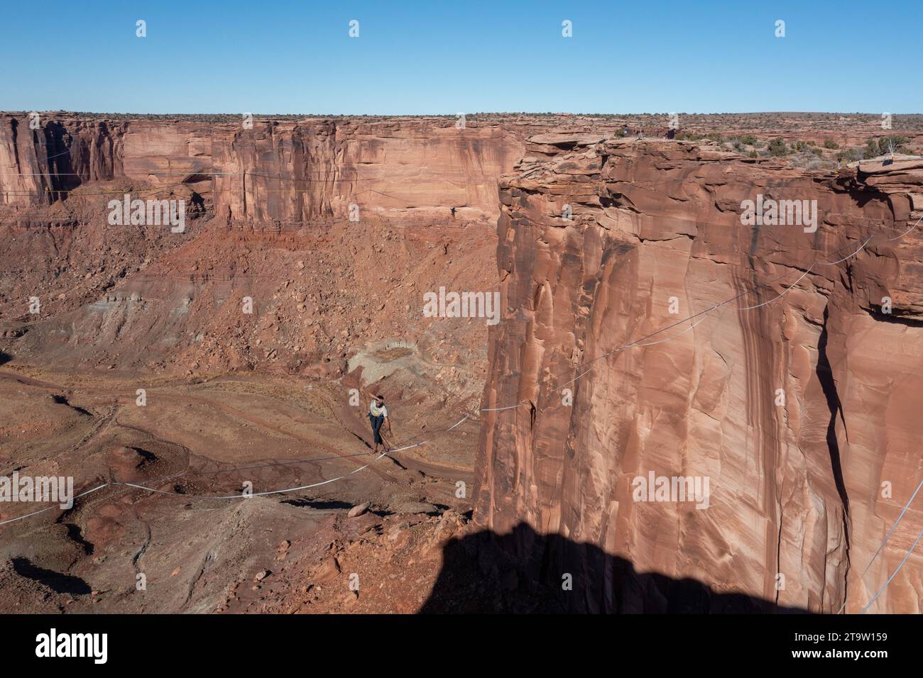 Aerial view of two people highlining 500 feet above the canyon floor at the GGBY Highline Festival near Moab, Utah. Stock Photo