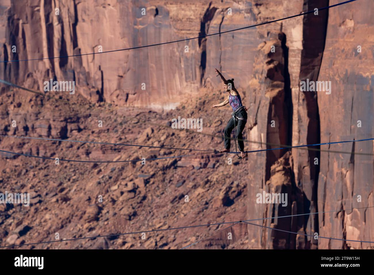 A woman walks the highline 500 feet above Mineral Canyon at the GGBY World Highline Festival near Moab, Utah. Stock Photo