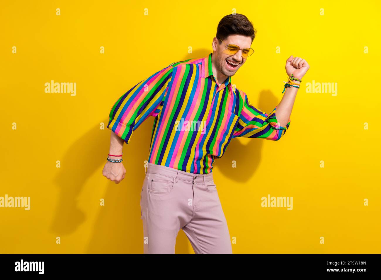 Photo of young guy in striped vintage shirt with pink pants dance his favorite music at summer