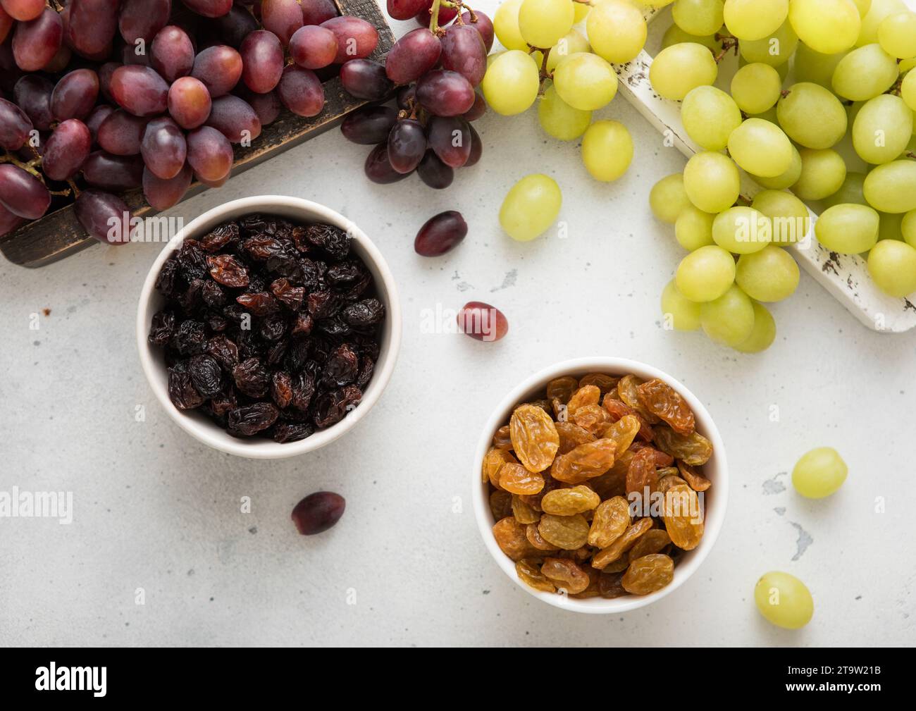 Sweet dried green and red dark raisins with ripe raw grapes on light ...